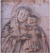 Antico rilievo in pietra della Madonna di Romania collocato sulla porta laterale destra della Cattedrale.